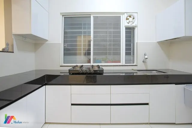 A white kitchen with dark worktops and a window above the cooking area.