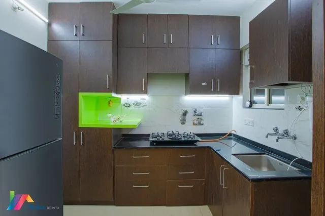 A kitchen with dark cabinetry and a bright green accent cabinet.