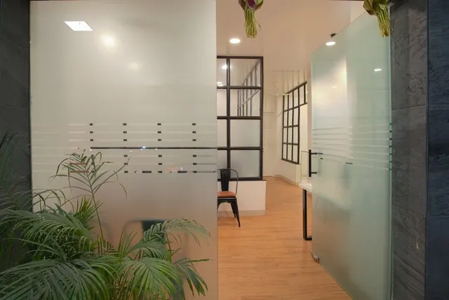 Clinic corridor with glass partitions and a timber floor.