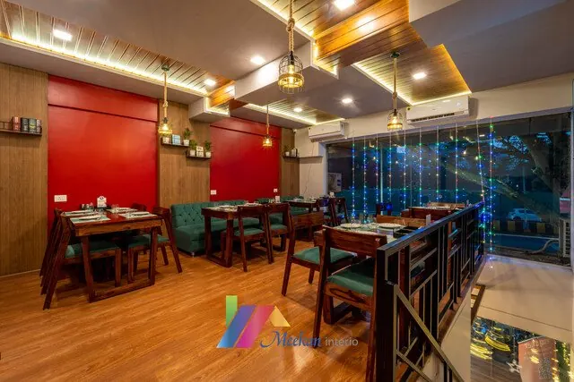 Restaurant tables beside a red wall and a window overlooking greenery.