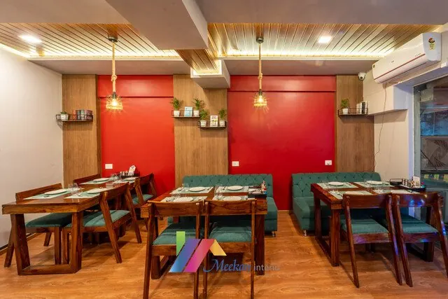 Restaurant with timber tables, a red feature wall and hanging lights.