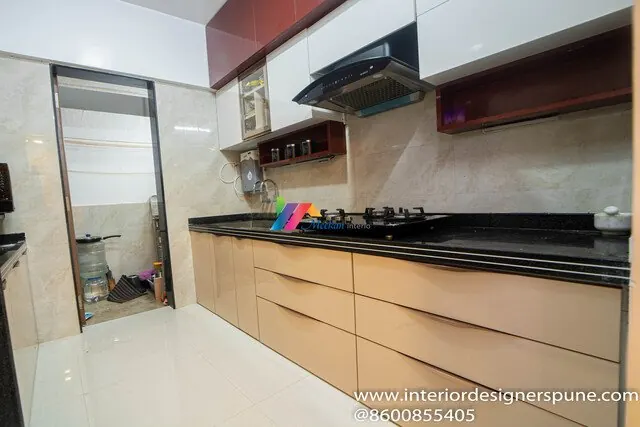 A kitchen with pale drawers, a dark worktop and wall-mounted open shelves.