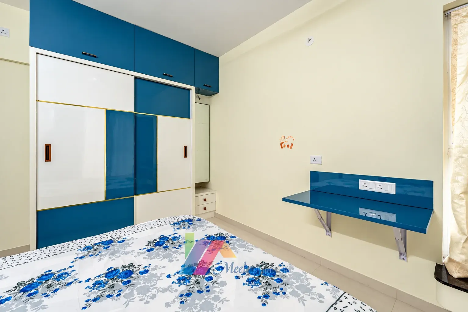 Bedroom with a blue-and-white sliding wardrobe and wall-mounted study desk.
