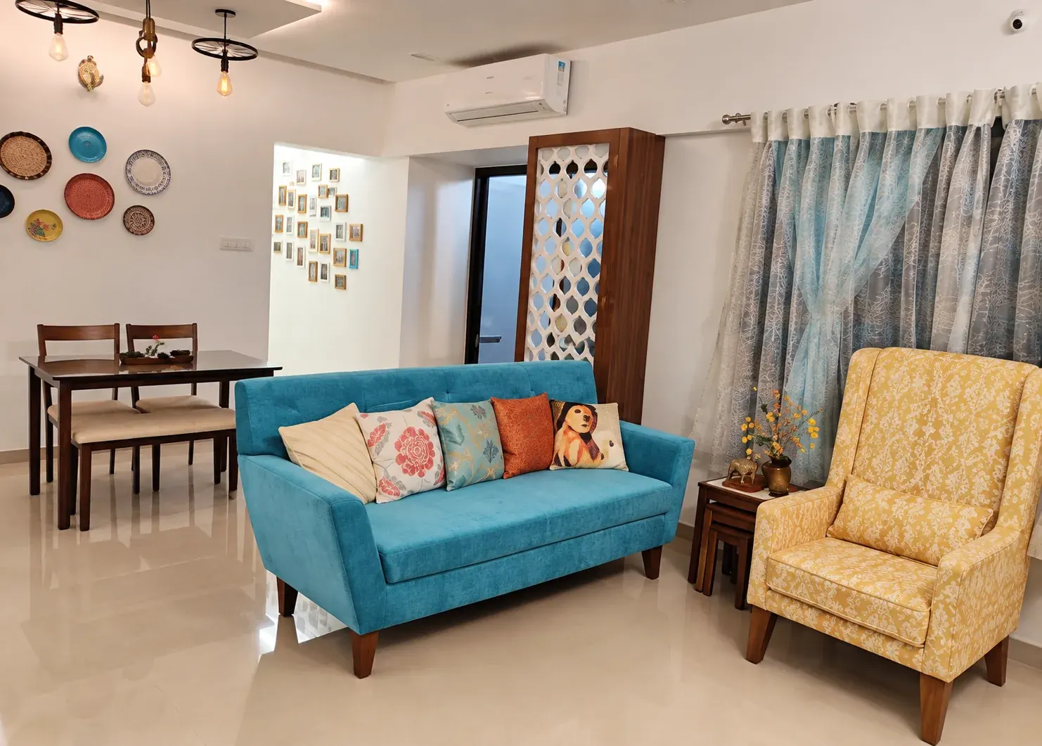 Living room with a turquoise sofa, yellow armchair and dining area beyond.