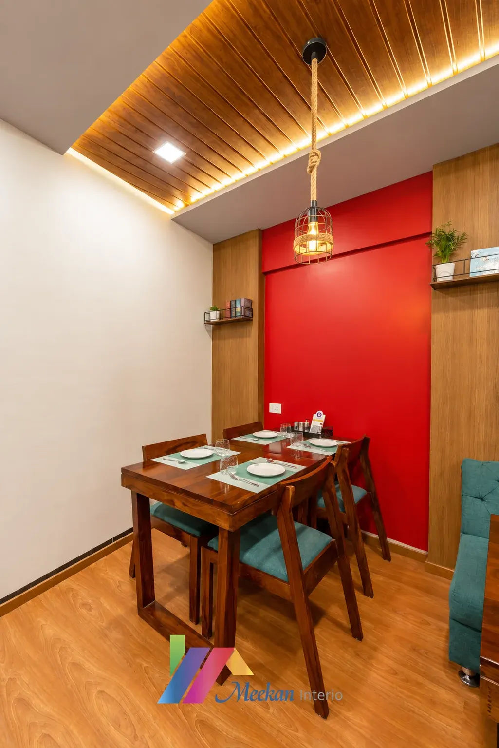 A dining nook with a red accent wall, timber ceiling, pendant light and four-place table.