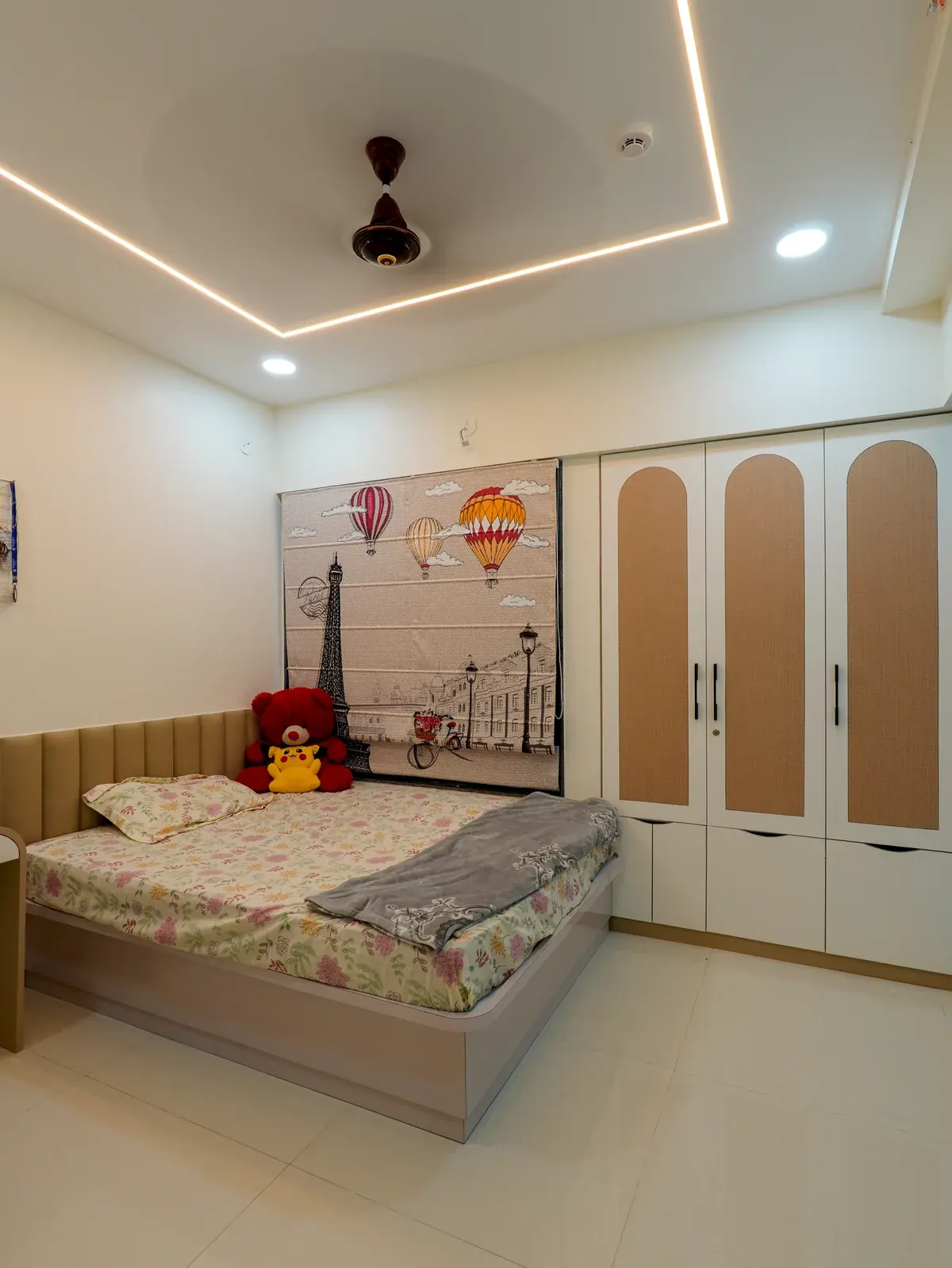 A bedroom with a colourful illustrated wall, upholstered headboard and wardrobe with rounded peach panels.