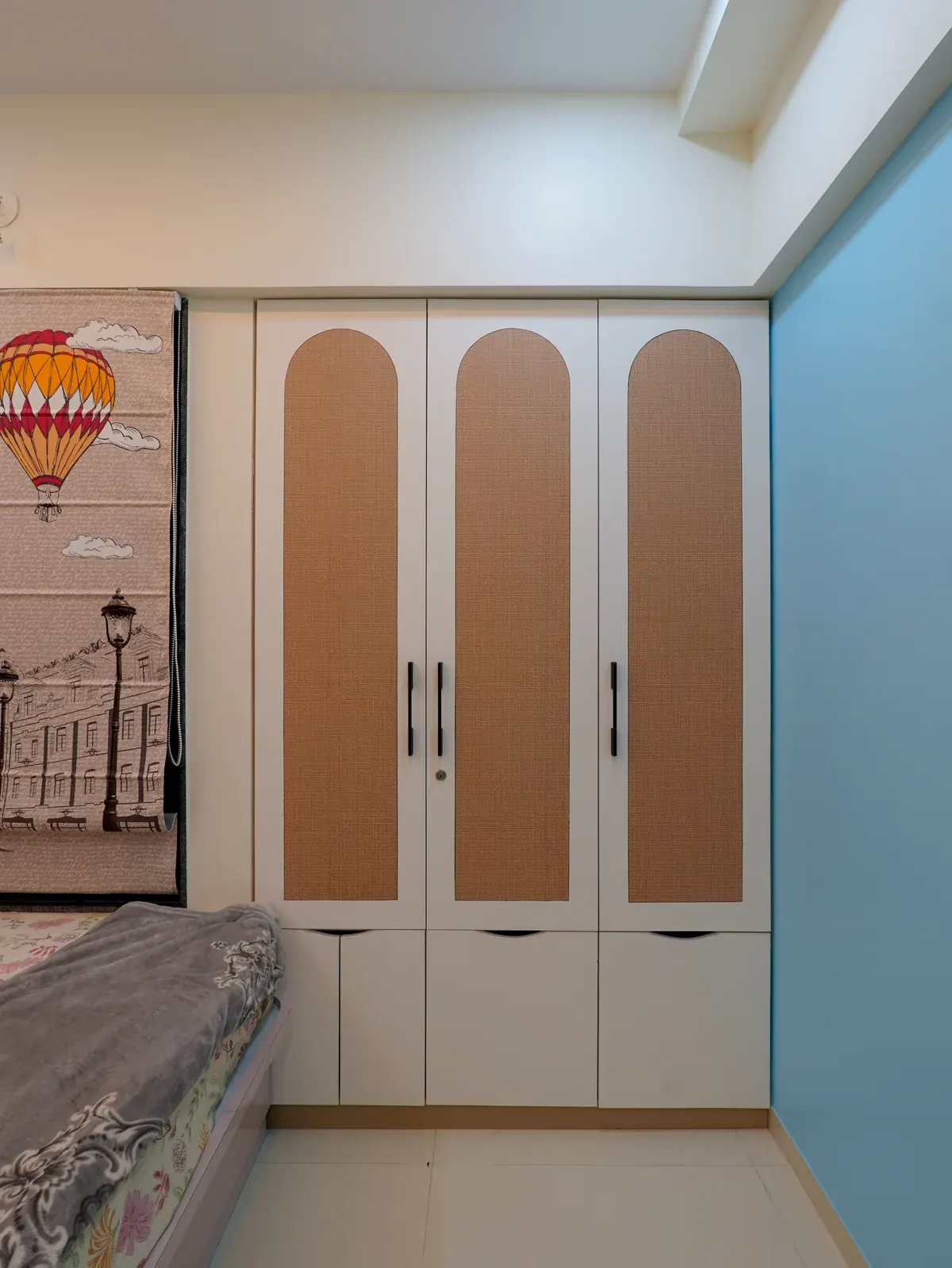 A white wardrobe with tall rounded peach panels and slim vertical handles.