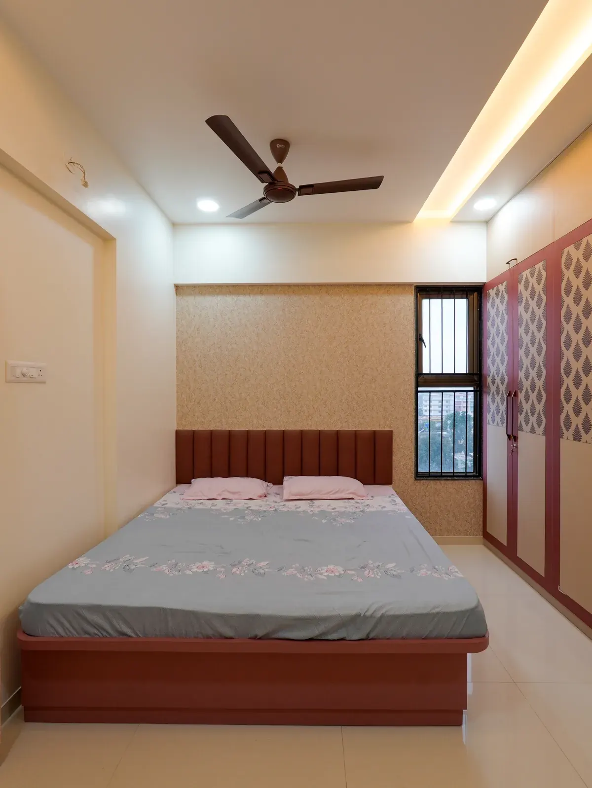 A timber bed and headboard framed by cream walls and layered ceiling lighting.