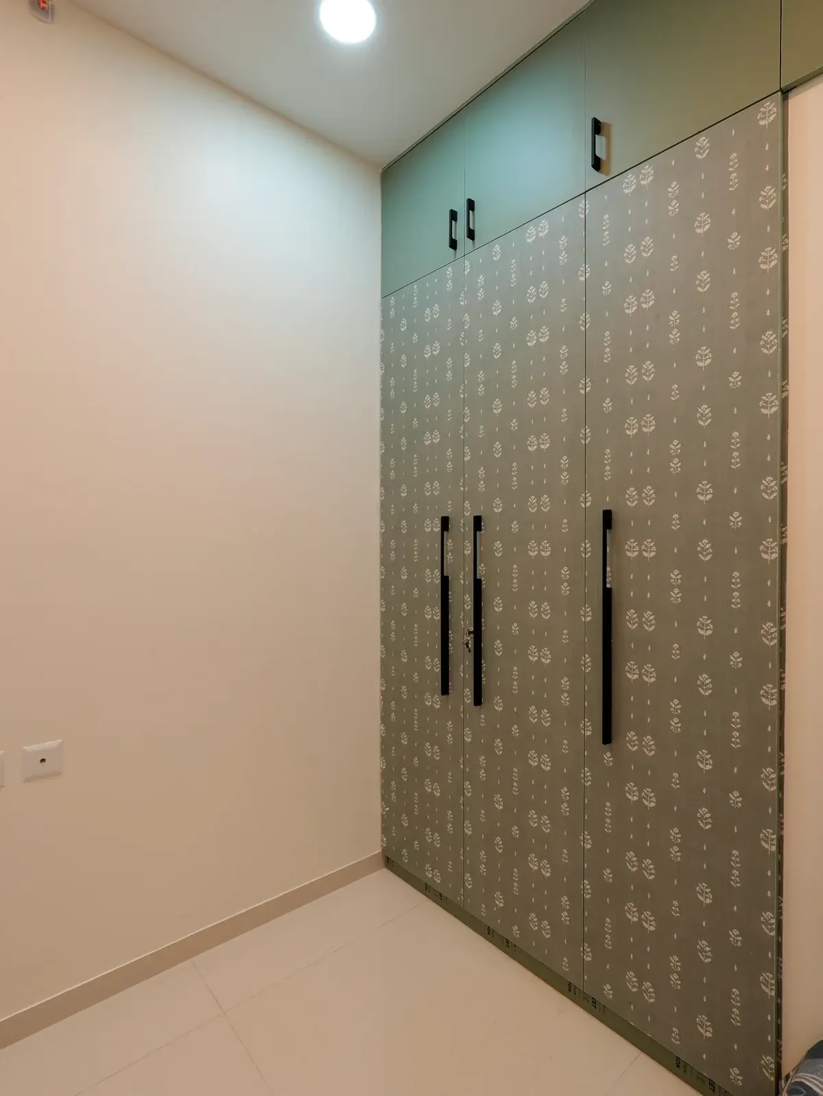 Full-height patterned wardrobe doors with dark handles and mint upper cabinets.