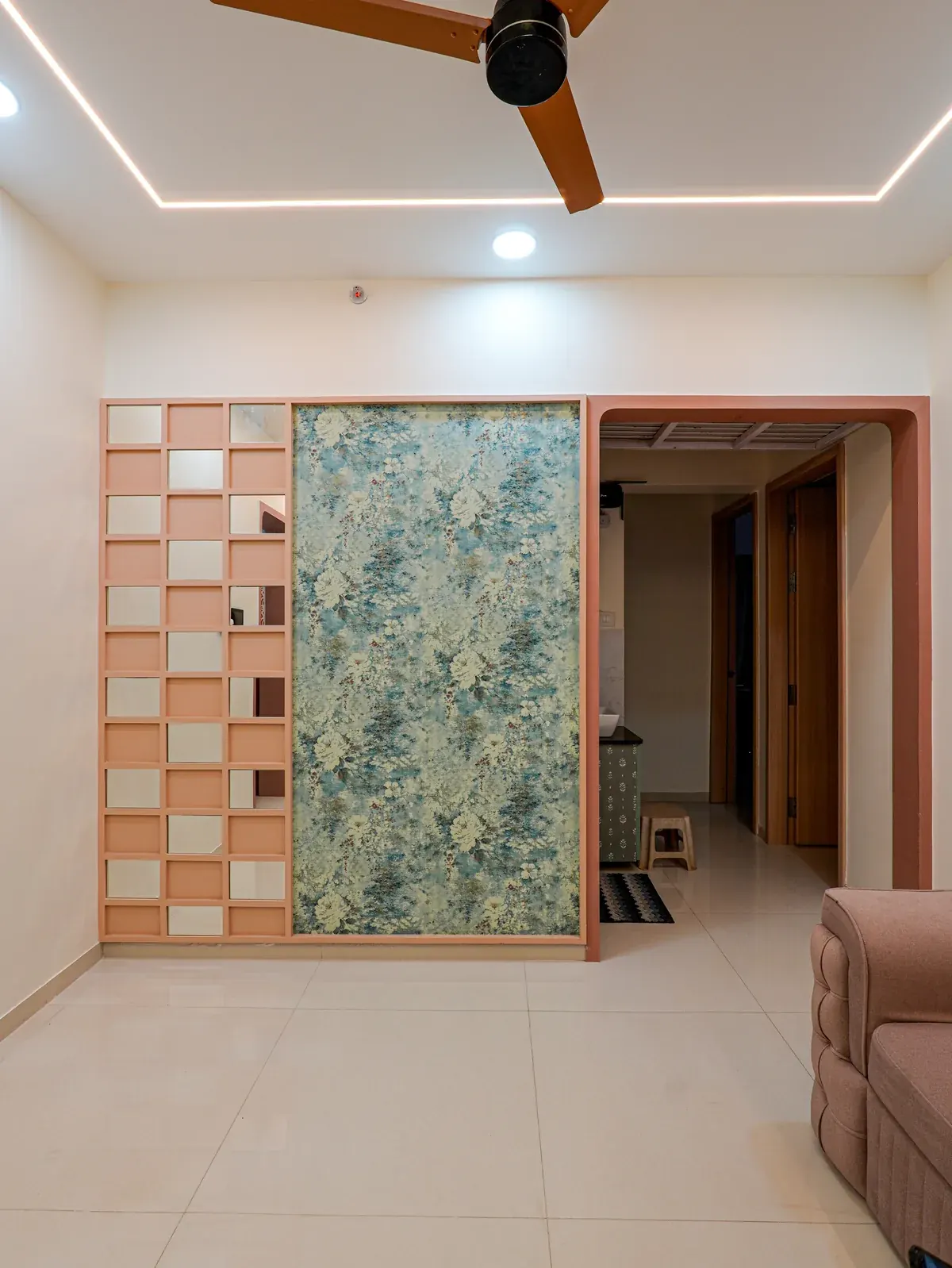 A decorative partition with mirrored squares and a botanical panel beside an open doorway.