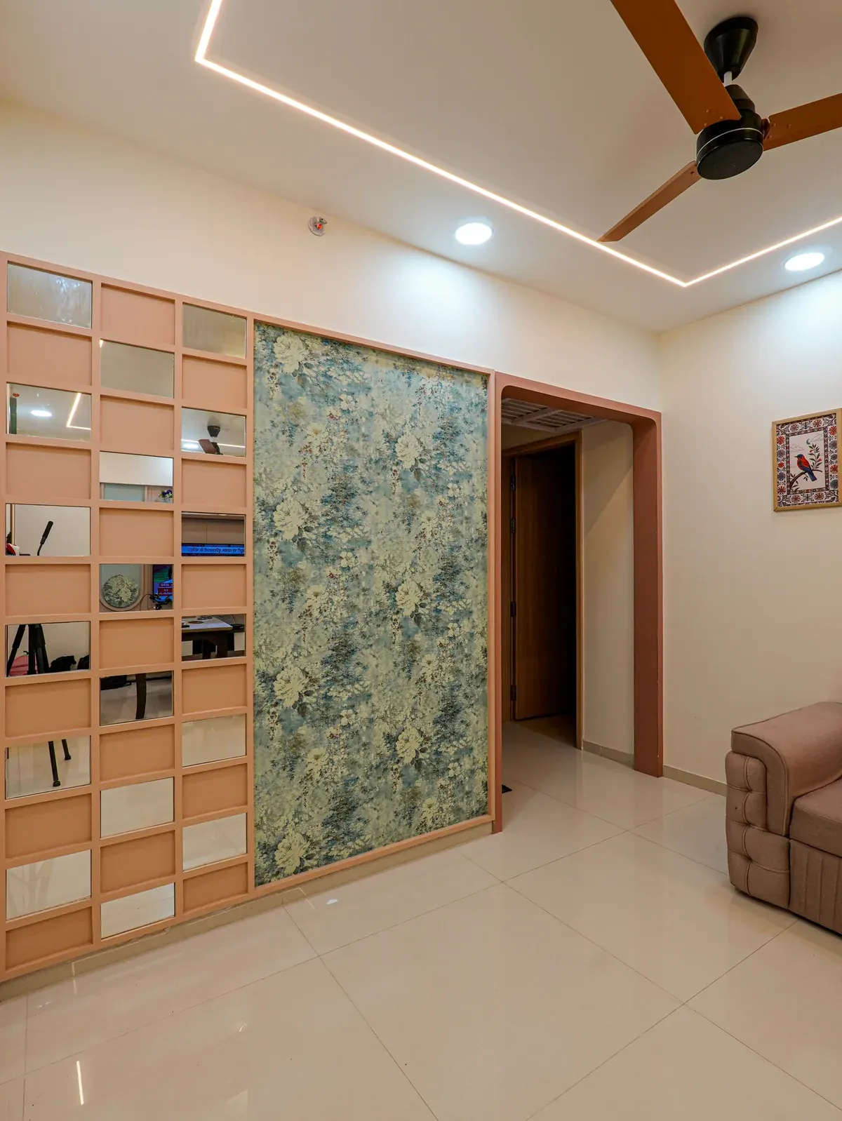 A living space with a grid of mirrored panels beside a blue-green botanical feature wall.