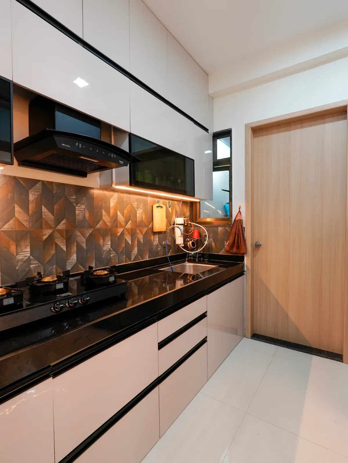 Kitchen cabinets and worktops arranged along the wall, with a chimney hood above the cooking area.
