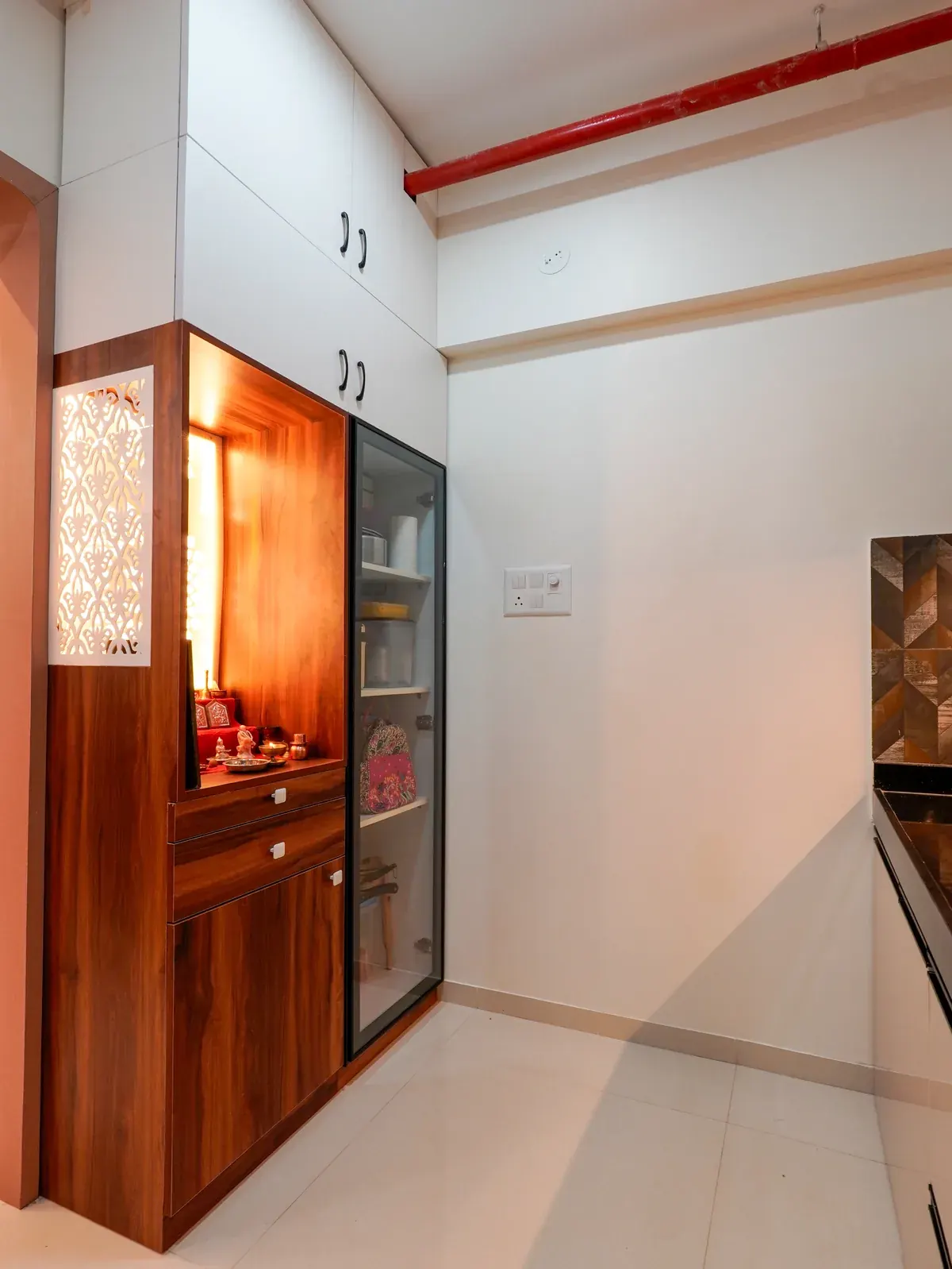 A timber prayer cabinet with illuminated doors beside the kitchen.
