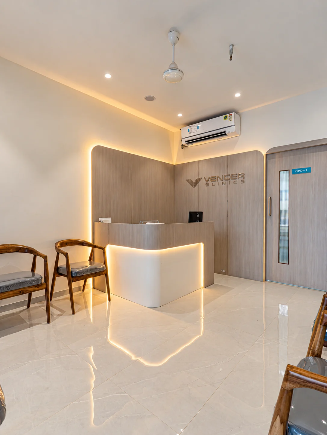 Clinic reception with a curved counter, illuminated wall panels and timber waiting chairs.